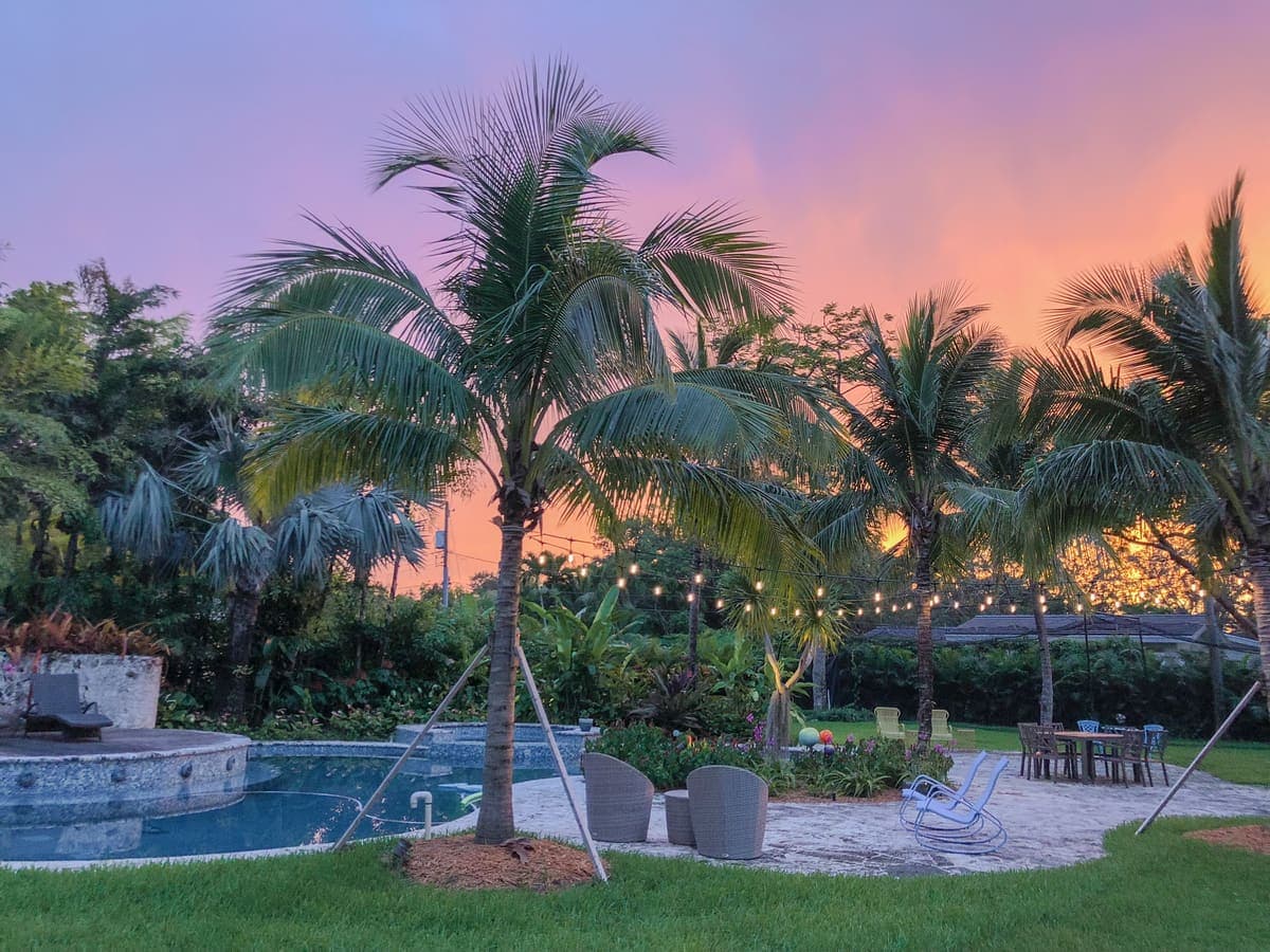 A Florida backyard with pool and string lights glowing at sunset