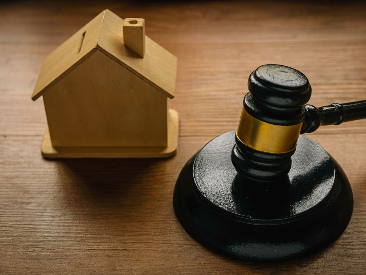 A judge's gavel resting in front of a model house