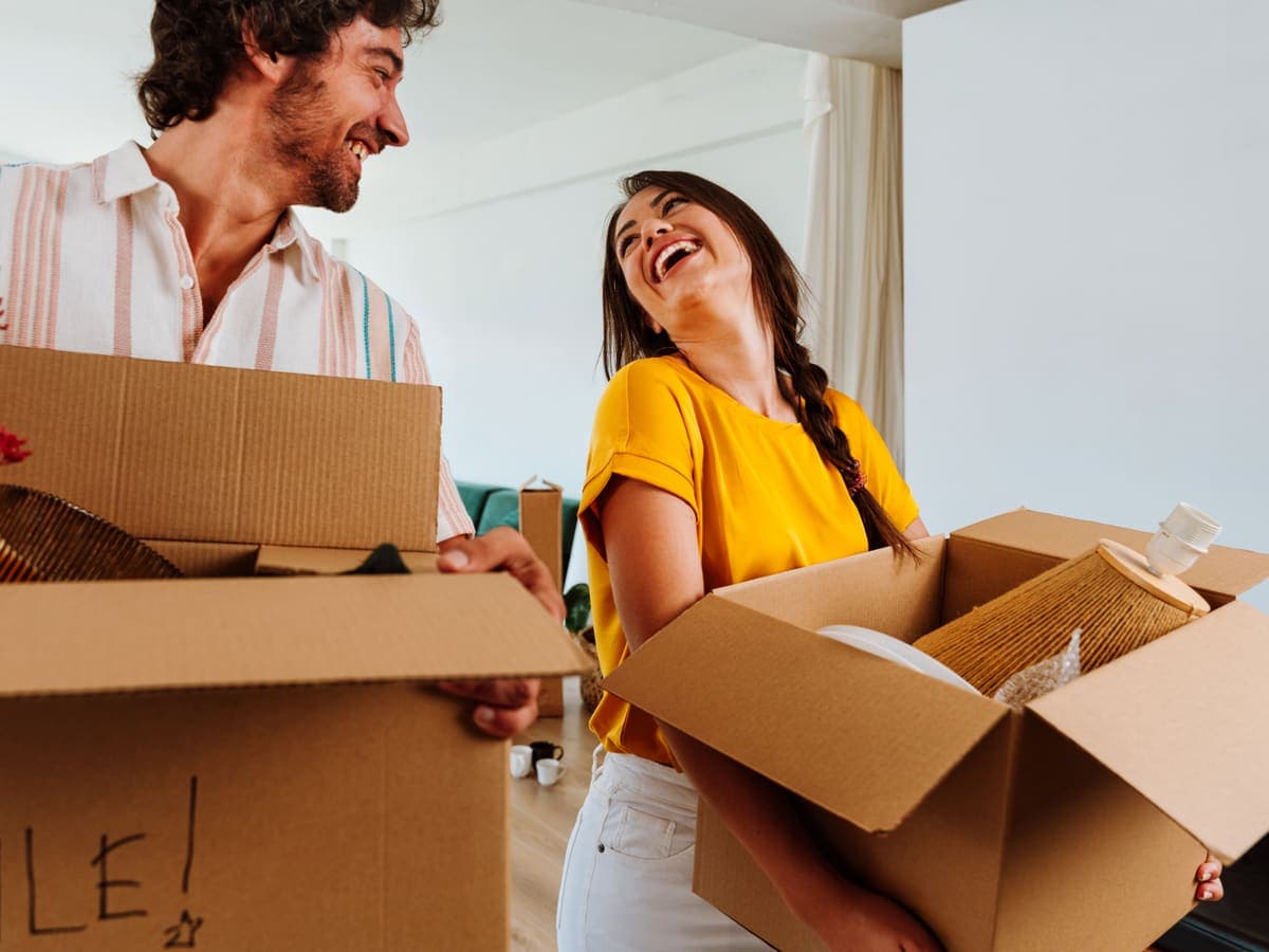 A couple carrying moving boxes into their new home
