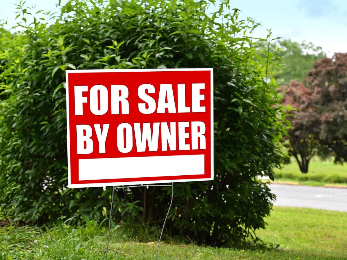A for sale by owner sign in a front yard